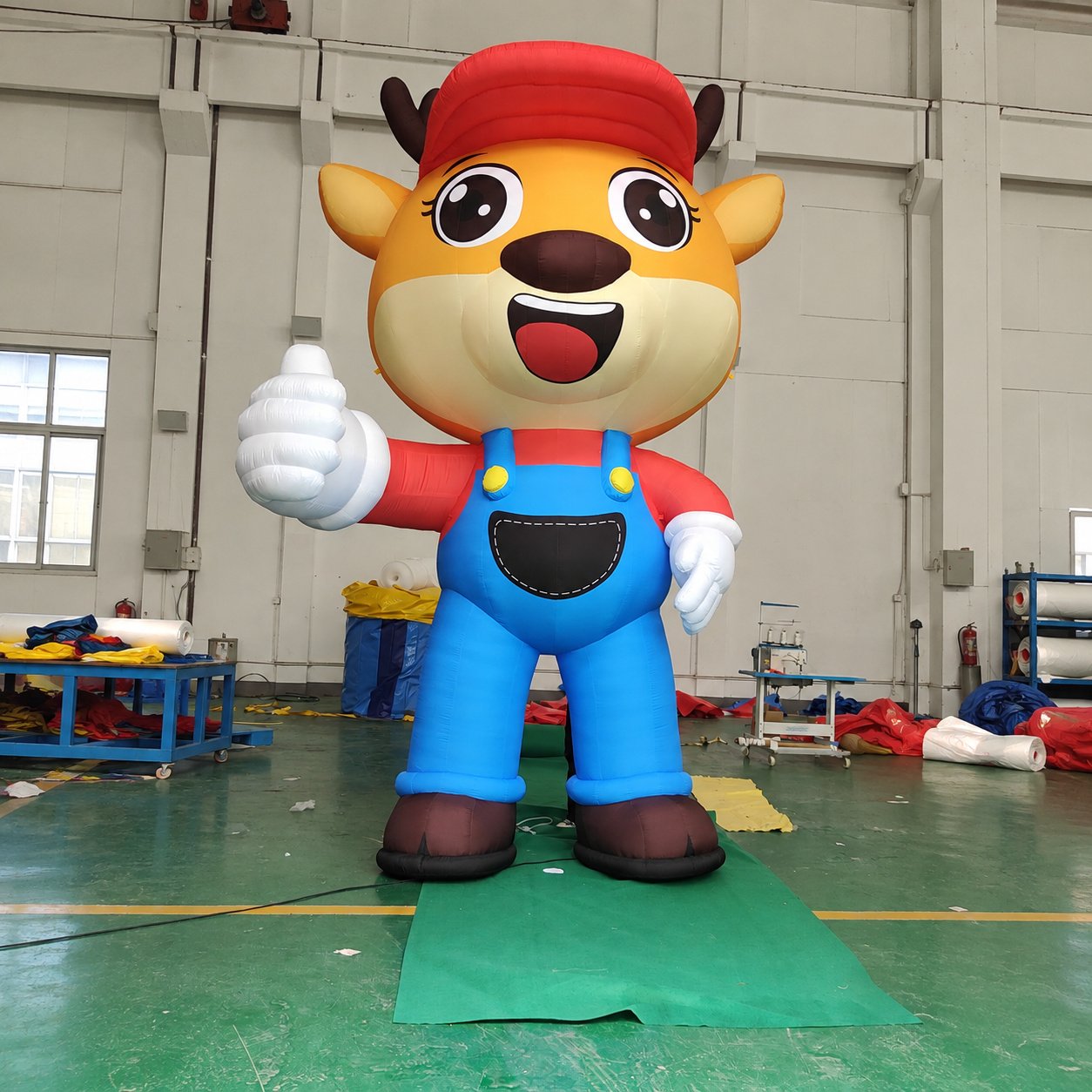 Inflatable antlered animal character wearing blue overalls and a red cap