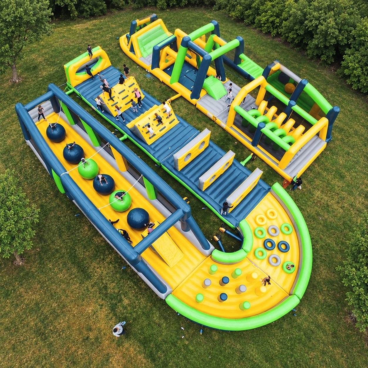 Aerial view of a green and yellow inflatable obstacle course with climbing walls and stepping balls