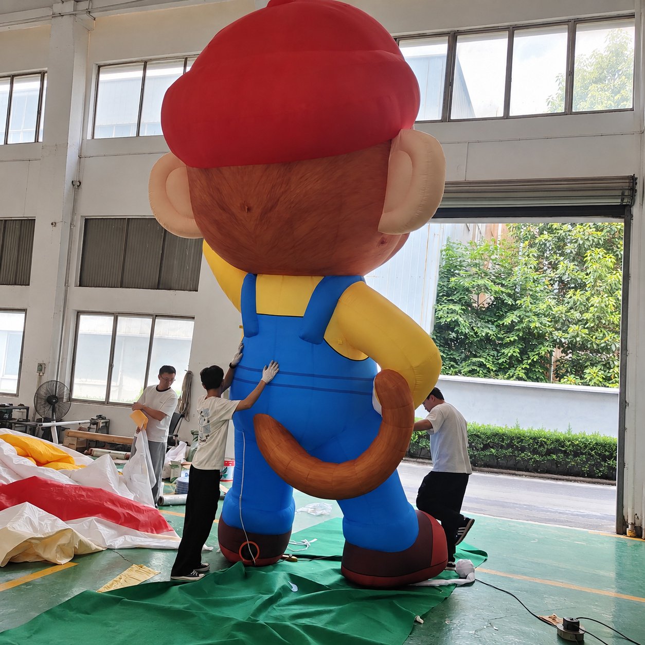 Rear view of an inflatable animal character wearing blue overalls and a red cap
