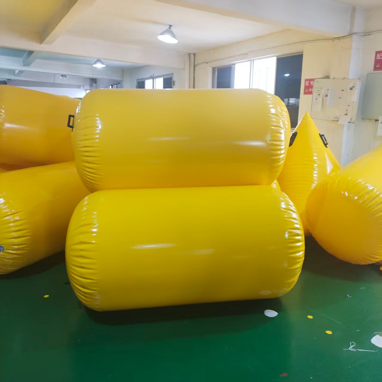 Stacked yellow inflatable cylindrical floats in a workshop