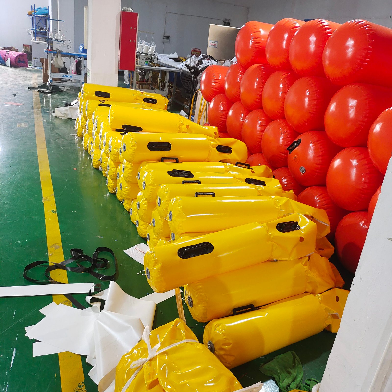 Yellow inflatable cylindrical floats with black handles in a factory