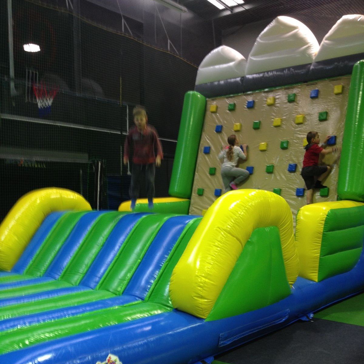 Green and blue inflatable climbing wall with an inflated landing area