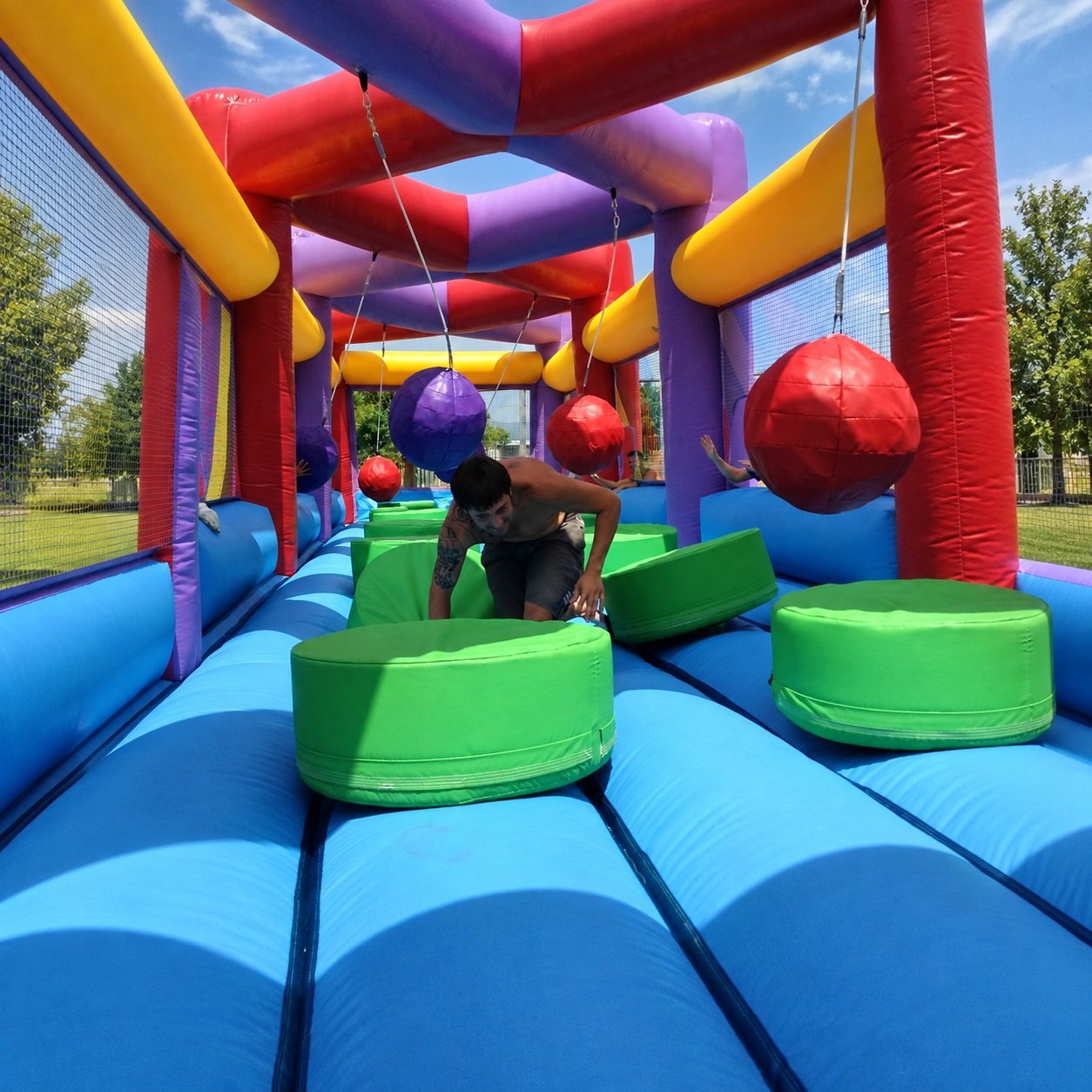 Inflatable obstacle course with green stepping pads and hanging red balls