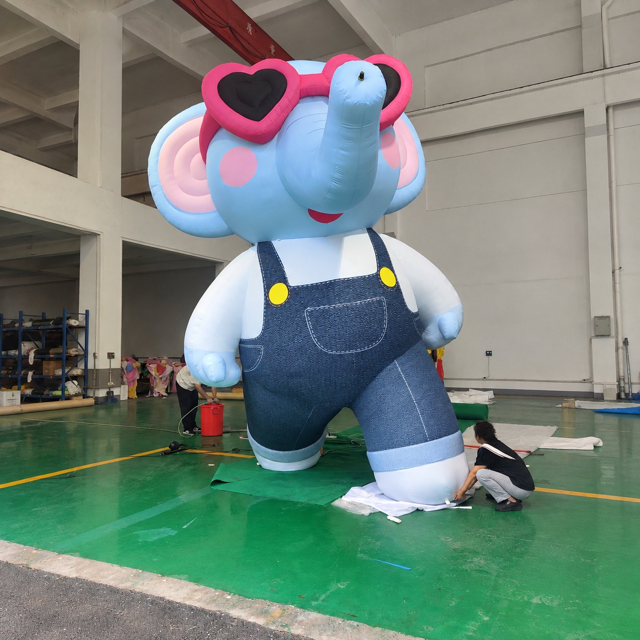 Blue inflatable elephant wearing overalls and pink heart-shaped sunglasses