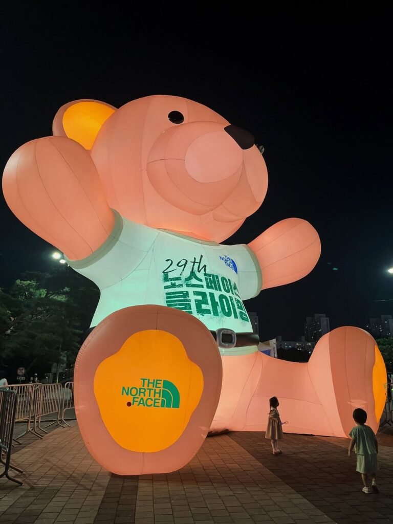 Giant illuminated inflatable teddy bear wearing a green shirt