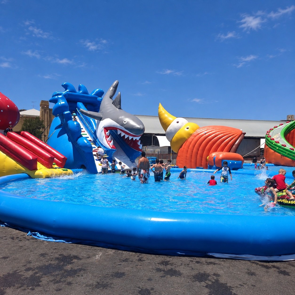 Inflatable water park with a shark-mouth slide and blue pool walls