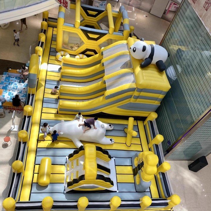 Yellow and gray inflatable obstacle course with a panda-topped slide