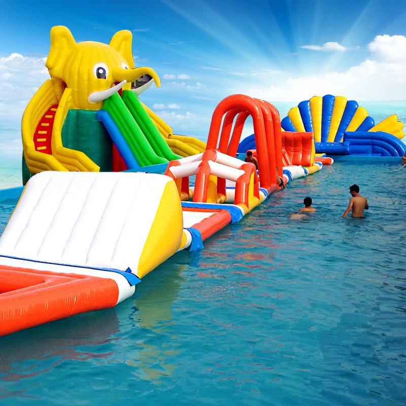 Colorful inflatable water obstacle course beside an elephant-themed slide