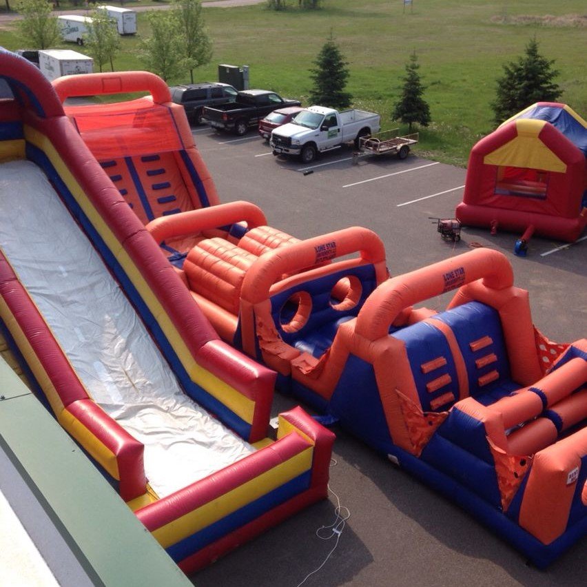 Red and blue inflatable obstacle course beside a tall slide