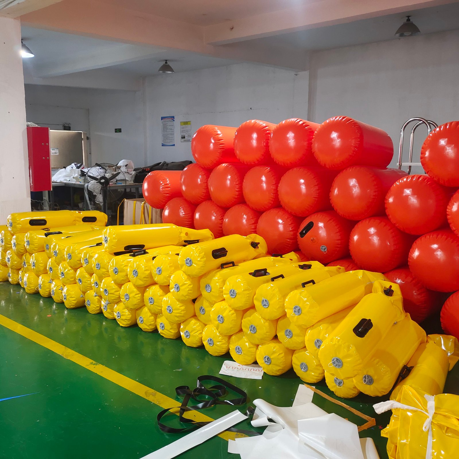 Stacks of red and yellow inflatable cylindrical floats in a factory