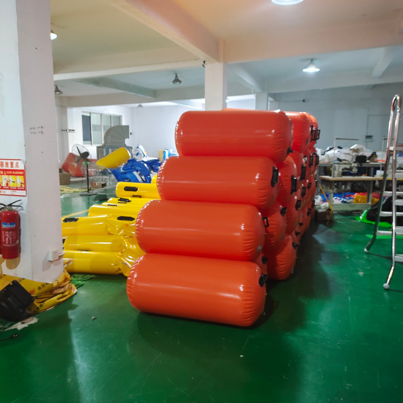 Stacked red inflatable cylindrical floats beside yellow floats