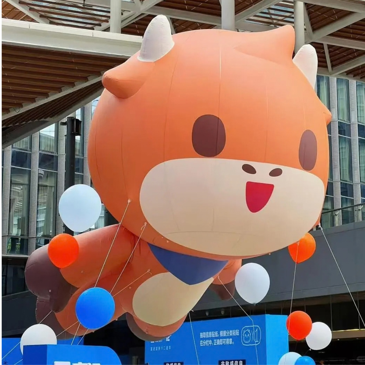Orange inflatable cartoon animal with horns and a blue outfit