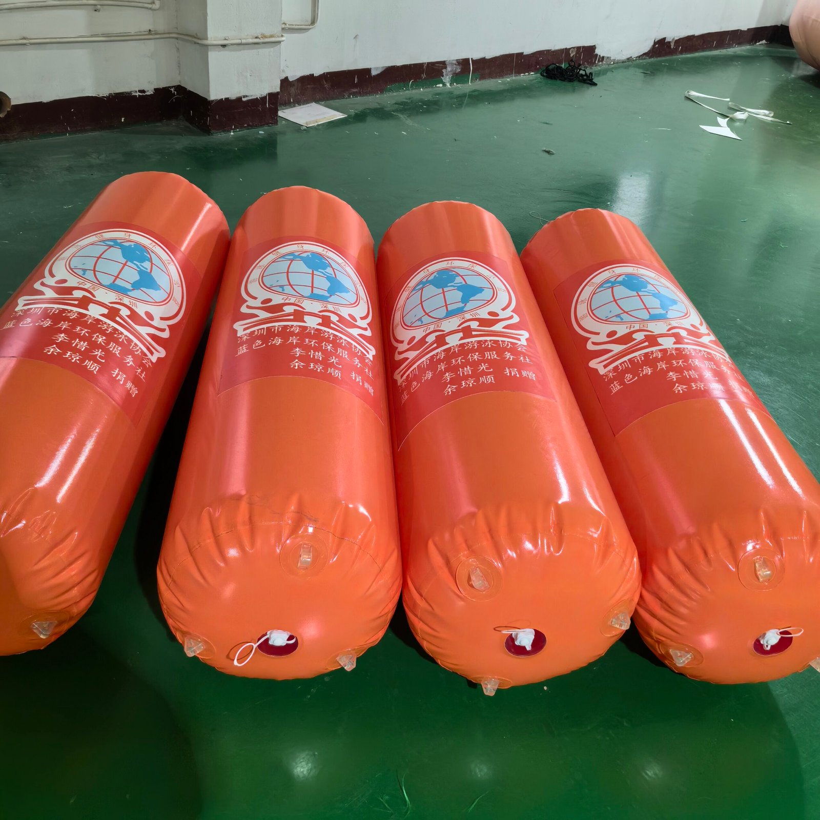 Orange cylindrical inflatable marker buoys with printed logos