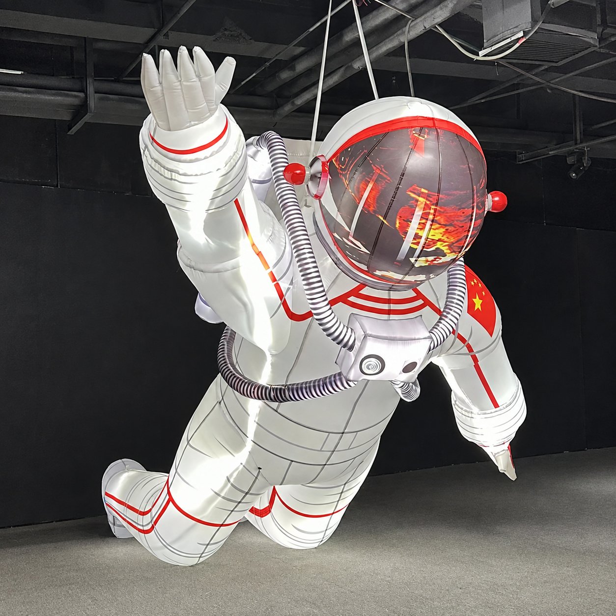 White inflatable astronaut with red trim suspended in a flying pose