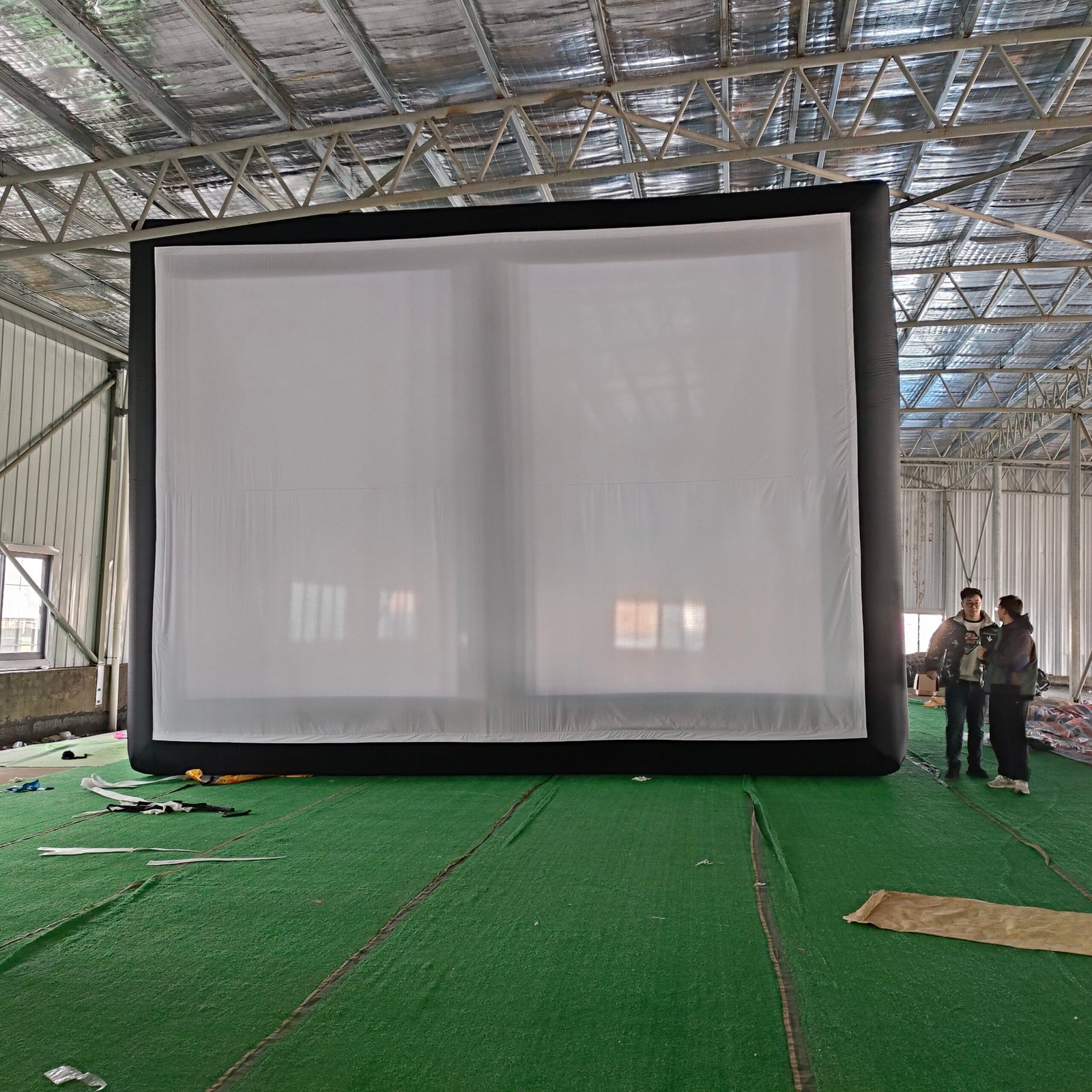 Large black-framed inflatable projection screen inside a factory