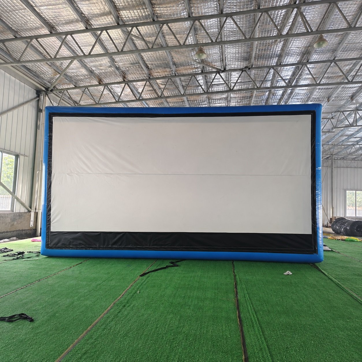 Front view of a blue-framed inflatable projection screen in a factory