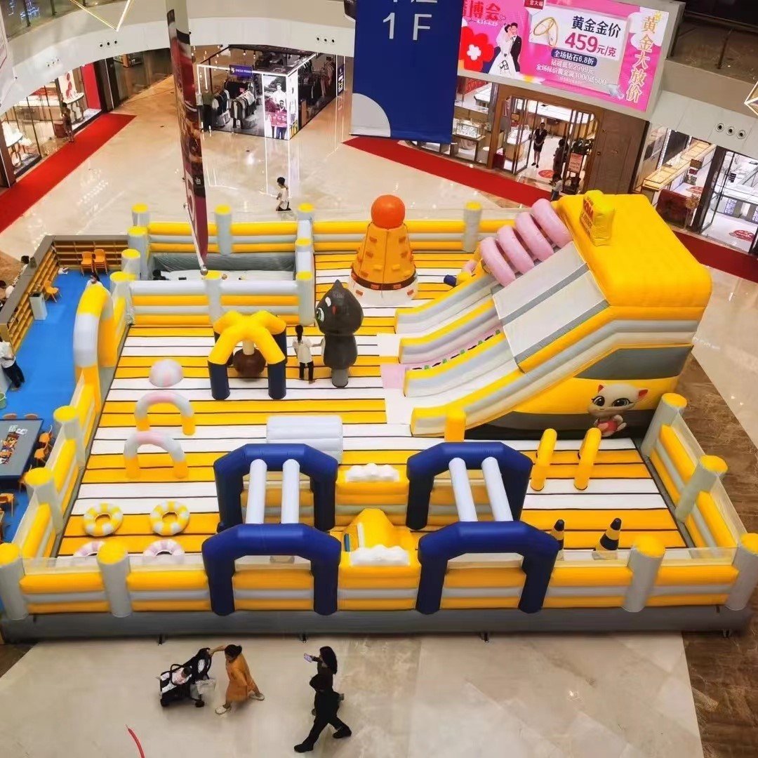 Yellow and gray inflatable obstacle course with slides inside a mall