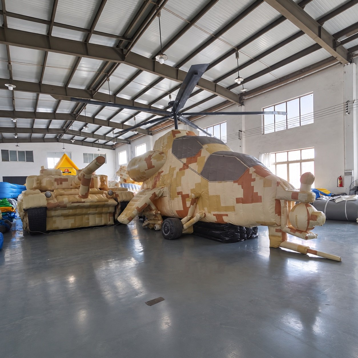 Camouflage inflatable helicopter and military vehicle models in a workshop