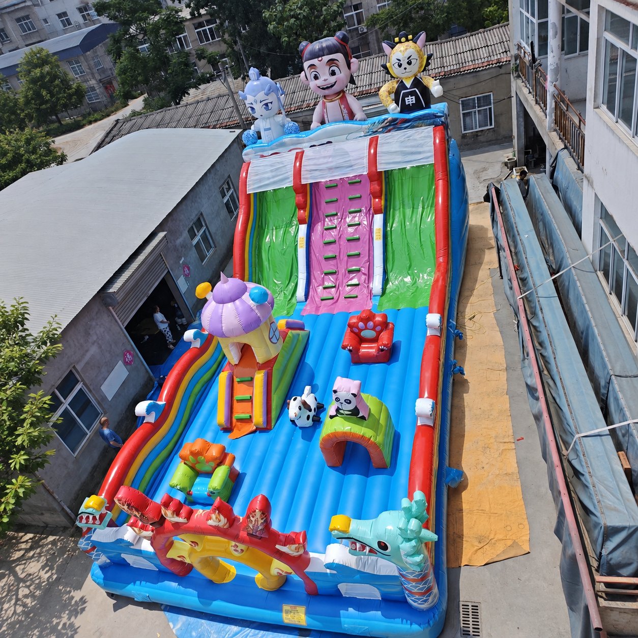 Long colorful inflatable play structure with slides and cartoon figures